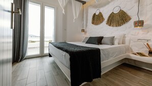 A modern bedroom with a large bed, a view through a sliding door, and a wall-mounted light fixture. - Hidden Gem, 2Br Family Villa, with Sea View | Naxos Mikri Vigla Beach (Naxos)