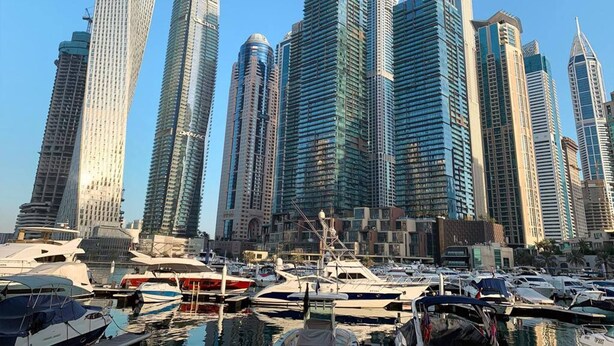 A marina with multiple boats docked, surrounded by high-rise buildings with modern architecture. - Lux High Rise Marina Apartment (Dubai)