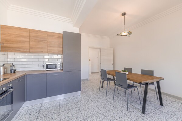 A modern kitchen with grey cabinets, a microwave, and a wooden countertop. - Harbour Vista: Spacious 2BR in Heart of Valletta (Valletta)