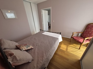 A bedroom with a bed, pillows, a chair, and a mirror.