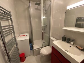 A modern bathroom with a glass shower enclosure, a white toilet, a red cabinet, and a white sink with a mirror above it. - Cozy studio near Linga cable car, with parking (Châtel)