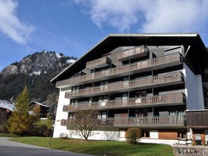 A multi-story building with balconies, set against a mountainous backdrop. - Cozy studio near Linga cable car, with parking (Châtel)