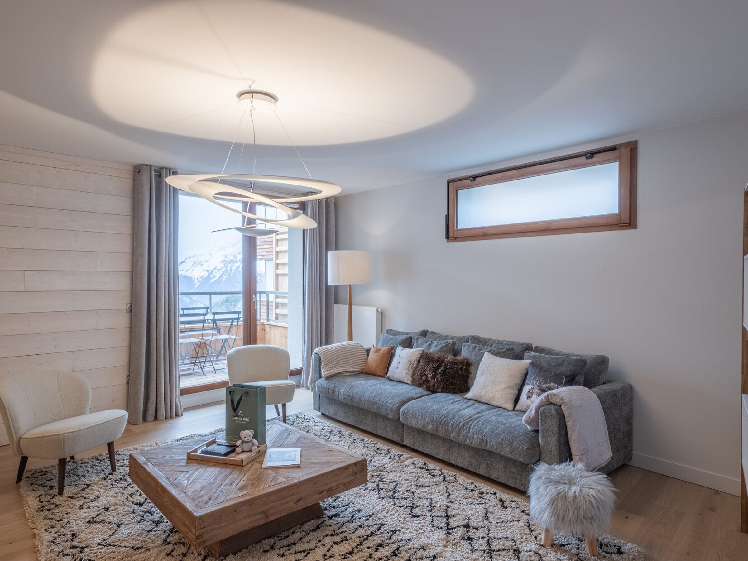 A modern living room with a grey sofa, a wooden coffee table, and a fluffy white dog.