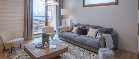 A modern living room with a grey sofa, a wooden coffee table, and a fluffy white dog.