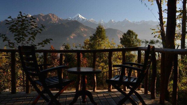 Une terrasse avec deux chaises et une table, offrant une vue sur une chaîne de montagnes.