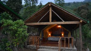 Un chalet rustique et chaleureux, avec une façade en bois, un chemin de pierres menant à l’entrée et un lit à baldaquin à l’intérieur.