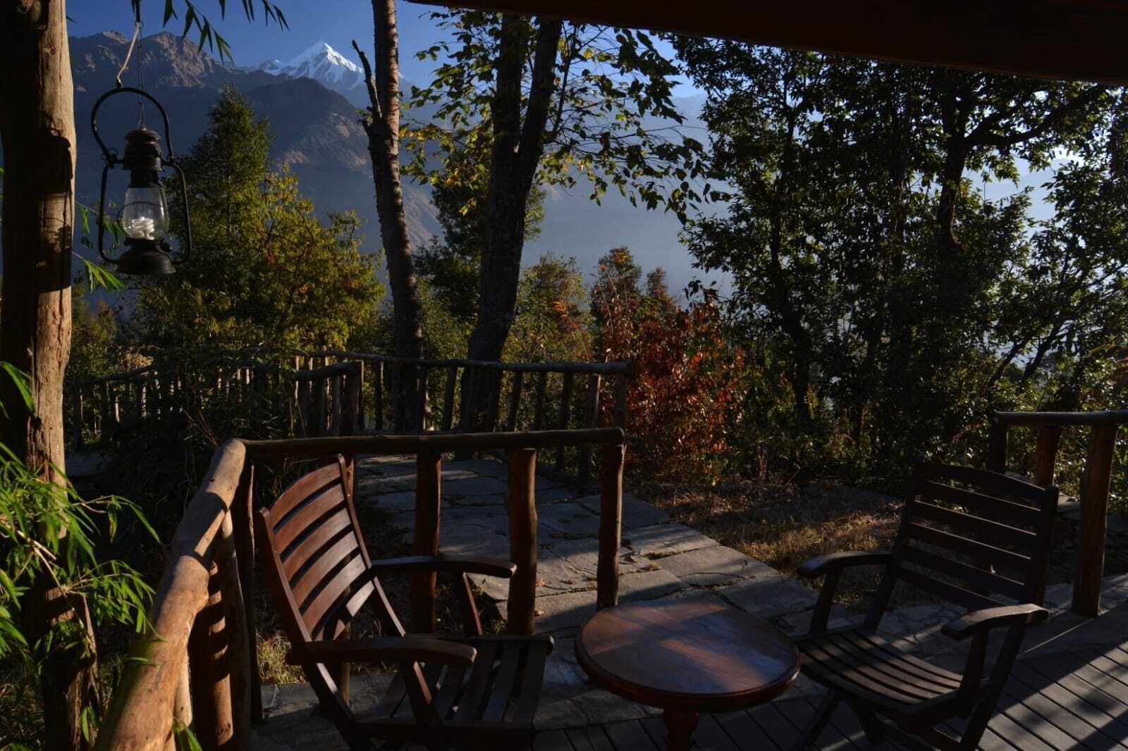 A wooden deck with a bench and a table, overlooking a mountainous landscape.