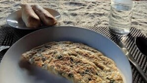 Une table à manger avec une assiette de nourriture, un verre d’eau et une vue sur l’extérieur.
