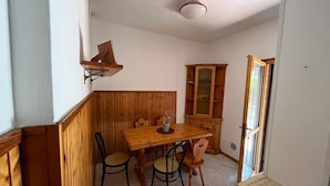 A dining area with a wooden table and chairs, a cabinet with a mirror, and a ceiling light fixture.