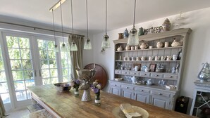 Een keuken met een houten keukeneiland, hanglampen en diverse keukengerei op planken.