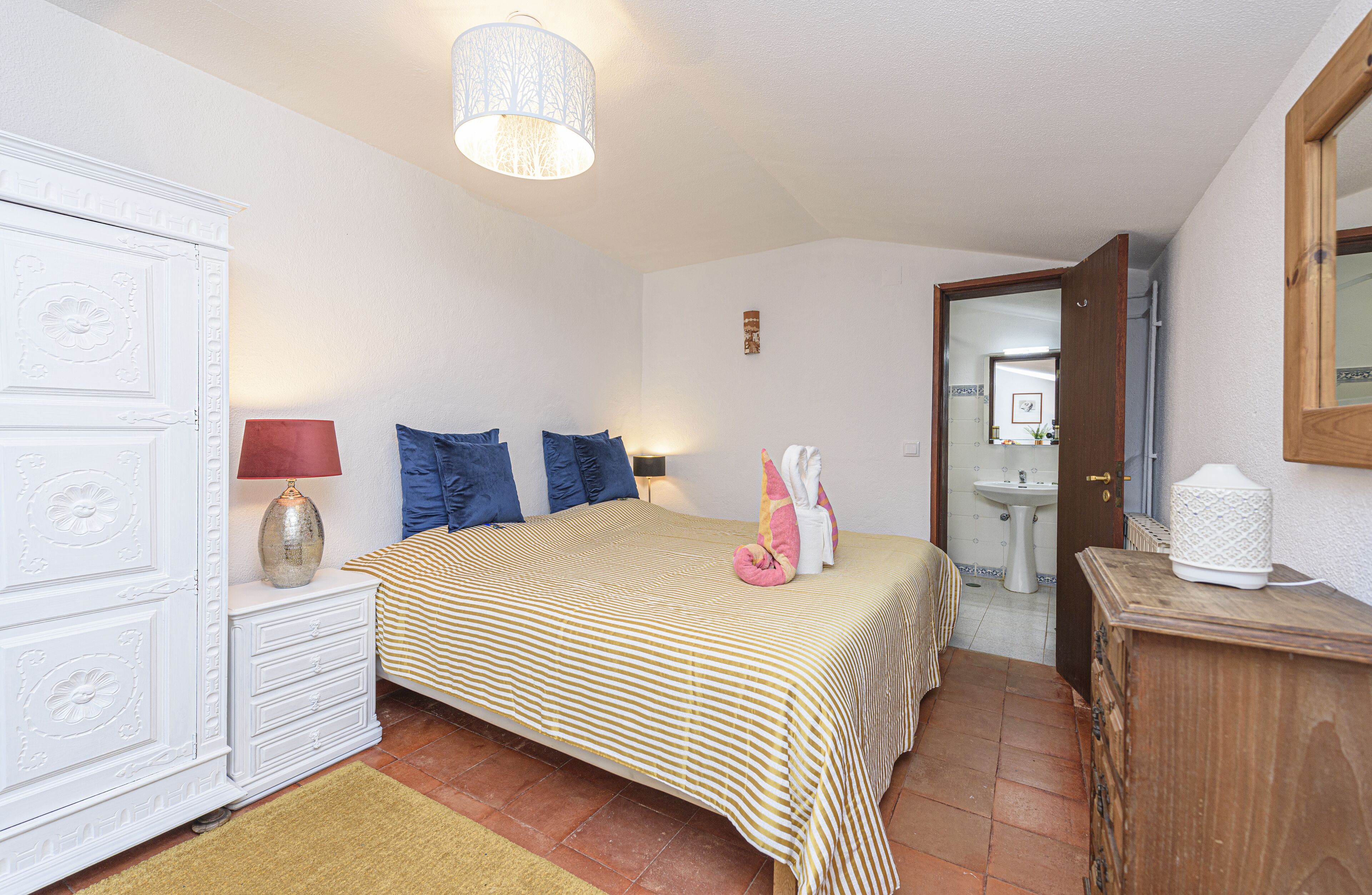 Une chambre à coucher avec un lit, des tables de chevet, une lampe et une armoire.