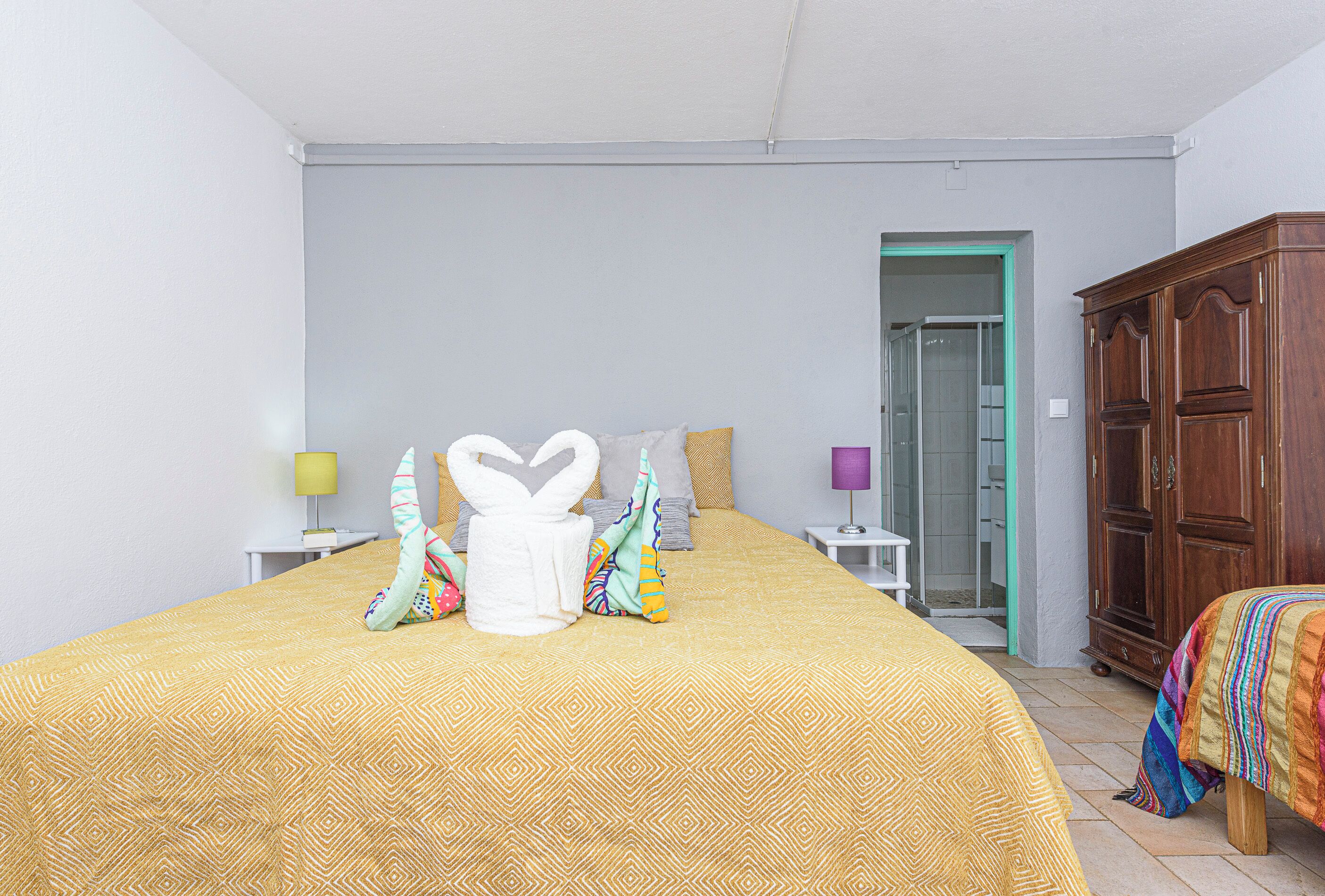 A hotel room with a large bed, a wardrobe, and a bathroom visible through an open door.