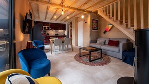 A modern living room with a sofa, a blue armchair, a coffee table, and a kitchen in the background. - Chalet Henri, Grand Confort, au Calme, vue D'exception, Sauna, 4/6 Personnes (Murol)