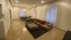A modern living room with a sectional sofa, a dining table, and a chandelier. - Luxury House With Parking (Napoli)