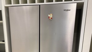 A stainless steel Whirlpool refrigerator with a freezer compartment on top and a bottom freezer compartment, located in a kitchen with white cabinetry and a tiled floor. - Luxury House With Parking (Napoli)