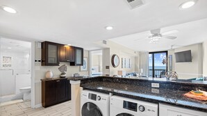 A modern kitchen with built-in appliances, a large window, and a ceiling fan.