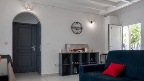 A modern living room with a dark blue sofa, a wooden coffee table, and a black clock on the wall.