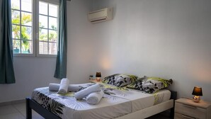A neatly made bed with rolled towels, a bedside lamp, and a window with curtains.