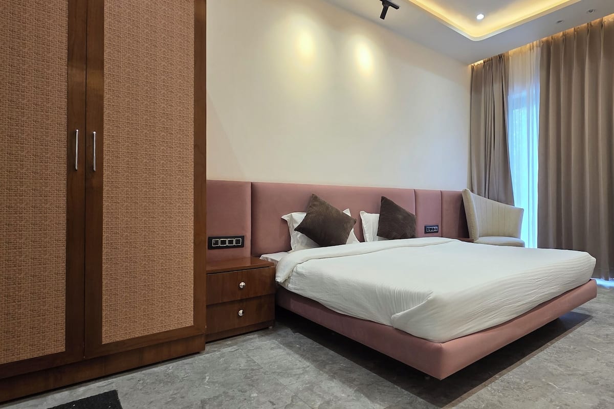Ein modernes Hotelzimmer mit einem großen Bett, einem Holzschrank, einem Nachttisch und einem an der Wand befestigten Fernseher.