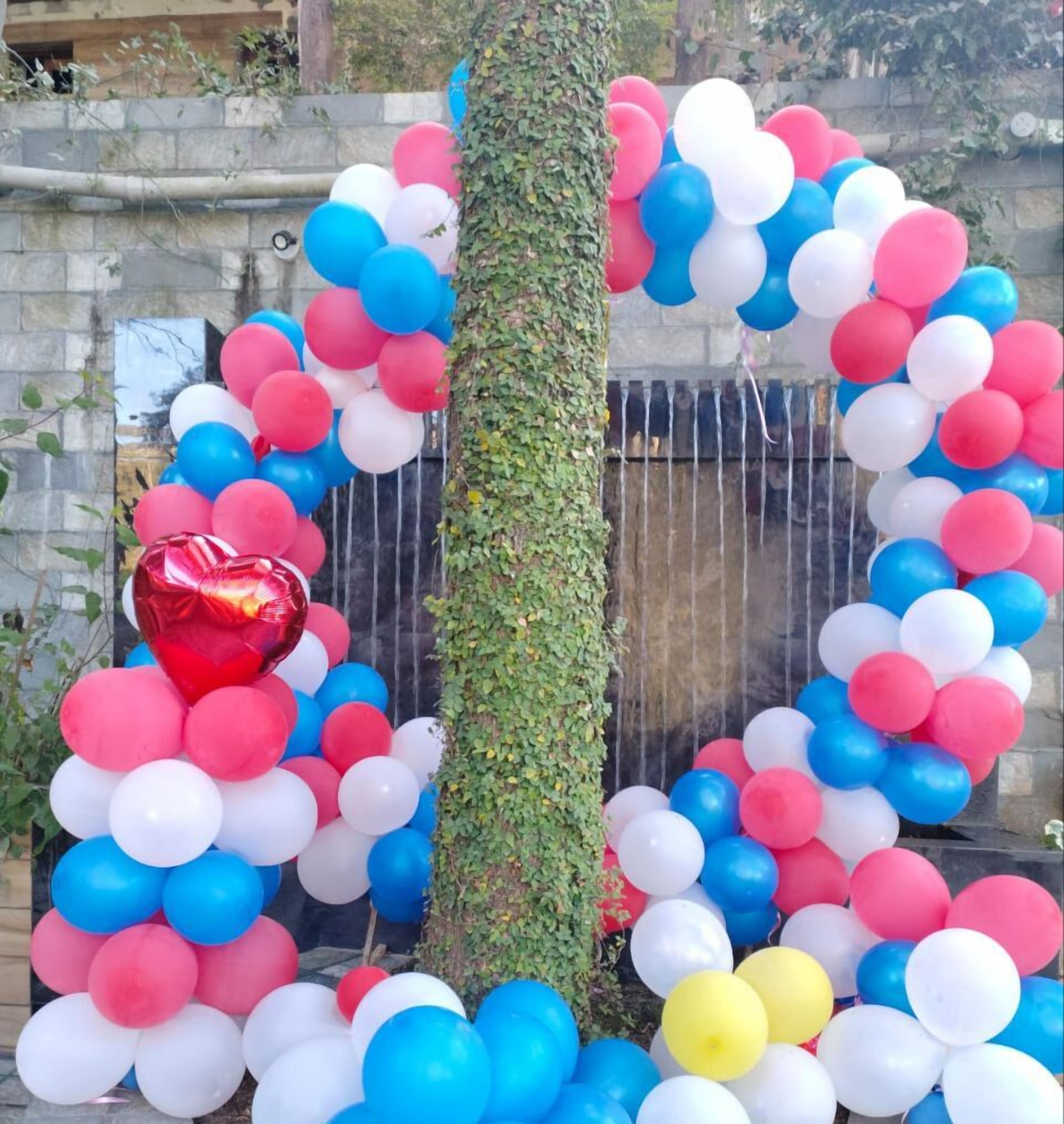 A tree surrounded by a heart-shaped balloon arrangement with red, white, and blue balloons.