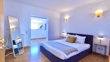 Un dormitorio moderno con una cama grande, lámparas de noche, un espejo y una ventana con vistas.