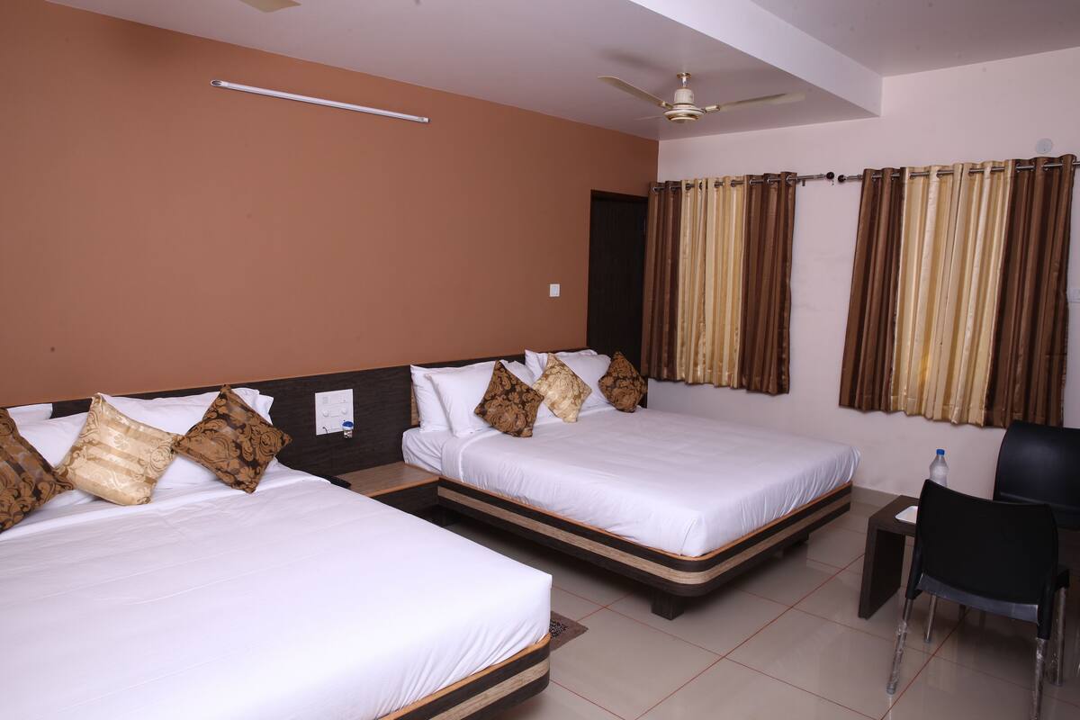 A hotel room with two beds, a desk, a chair, a ceiling fan, and curtains.