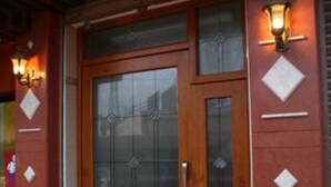 Una puerta de madera con paneles de vidrio y un felpudo verde en la entrada.