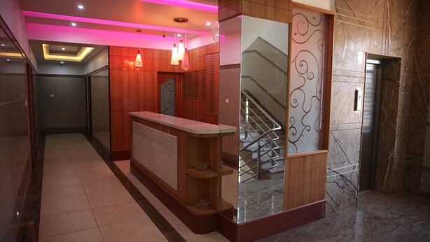 Una moderna zona de recepción con un mostrador de madera, un separador de vidrio y una pared de mármol.
