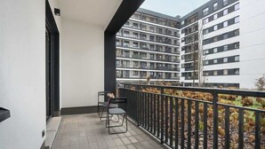 Ein Balkon mit schwarzer Metallreling, zwei Stühlen und einem kleinen Tisch.