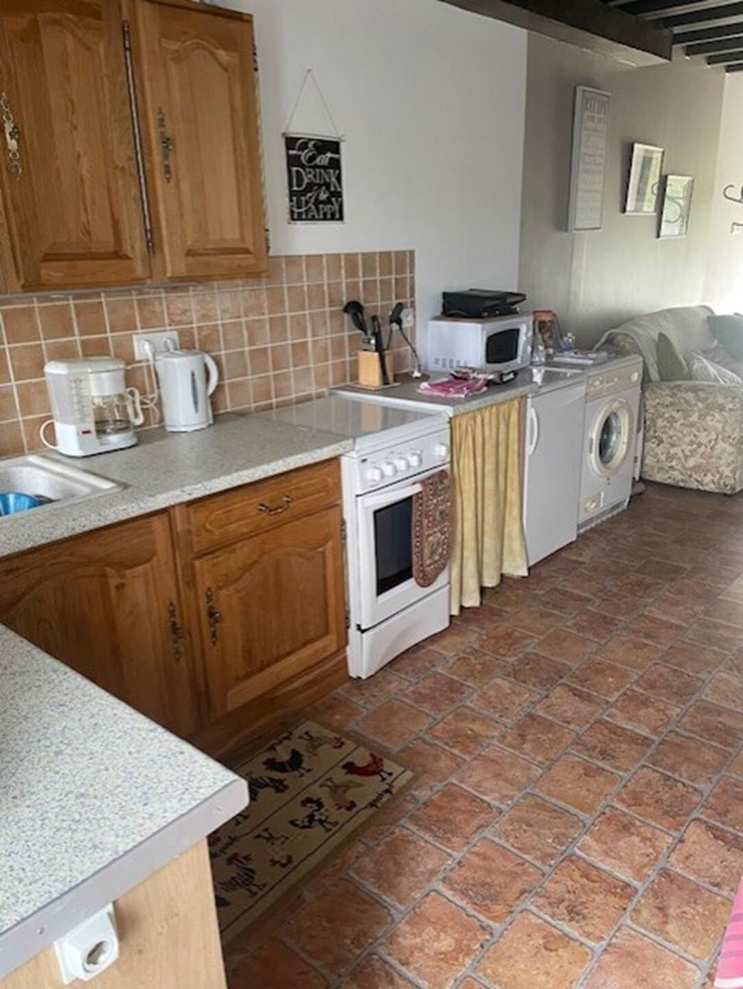A compact kitchen with wooden cabinets, a microwave, a stove, and a washing machine.