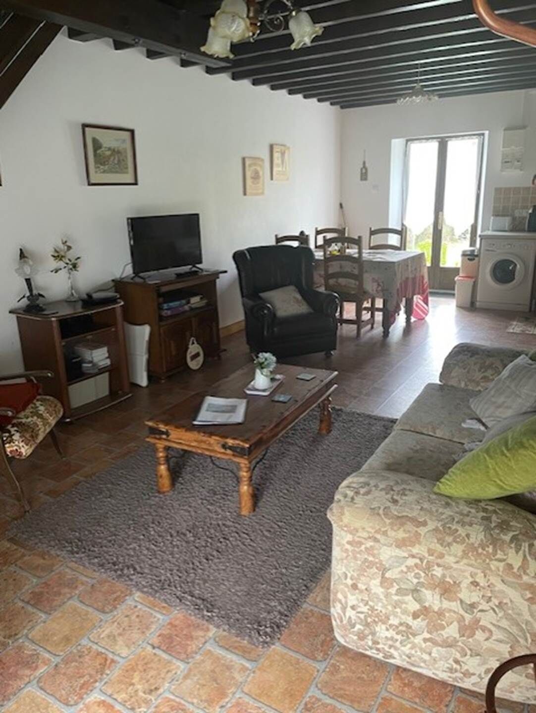 Una sala de estar con sofá, una mesa de centro, televisor, sillón y un área de comedor con mesa y sillas.