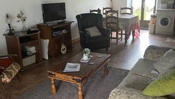 Una sala de estar con sofá, una mesa de centro, televisor, sillón y un área de comedor con mesa y sillas.