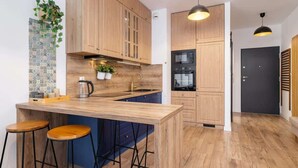 Una cocina moderna con armarios de madera, una isla central con taburetes, un microondas y un horno negro.