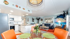 Una sala de estar moderna con comedor, cocina y un gran mural en la pared.
