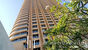 A tall, curved hotel building with a modern design, featuring a series of balconies and large windows.