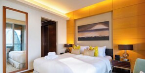 Une chambre d’hôtel de luxe avec un grand lit, des tables de chevet, un miroir et un tableau au mur.