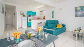 A modern living room with a teal sofa, a dining area with a glass table, and a kitchen with teal cabinets. - Verbena at the Refuge de Madiana in Schoelcher 1036 eg-supply-onboarding-api eg-supply-onboarding-api (Schoelcher)