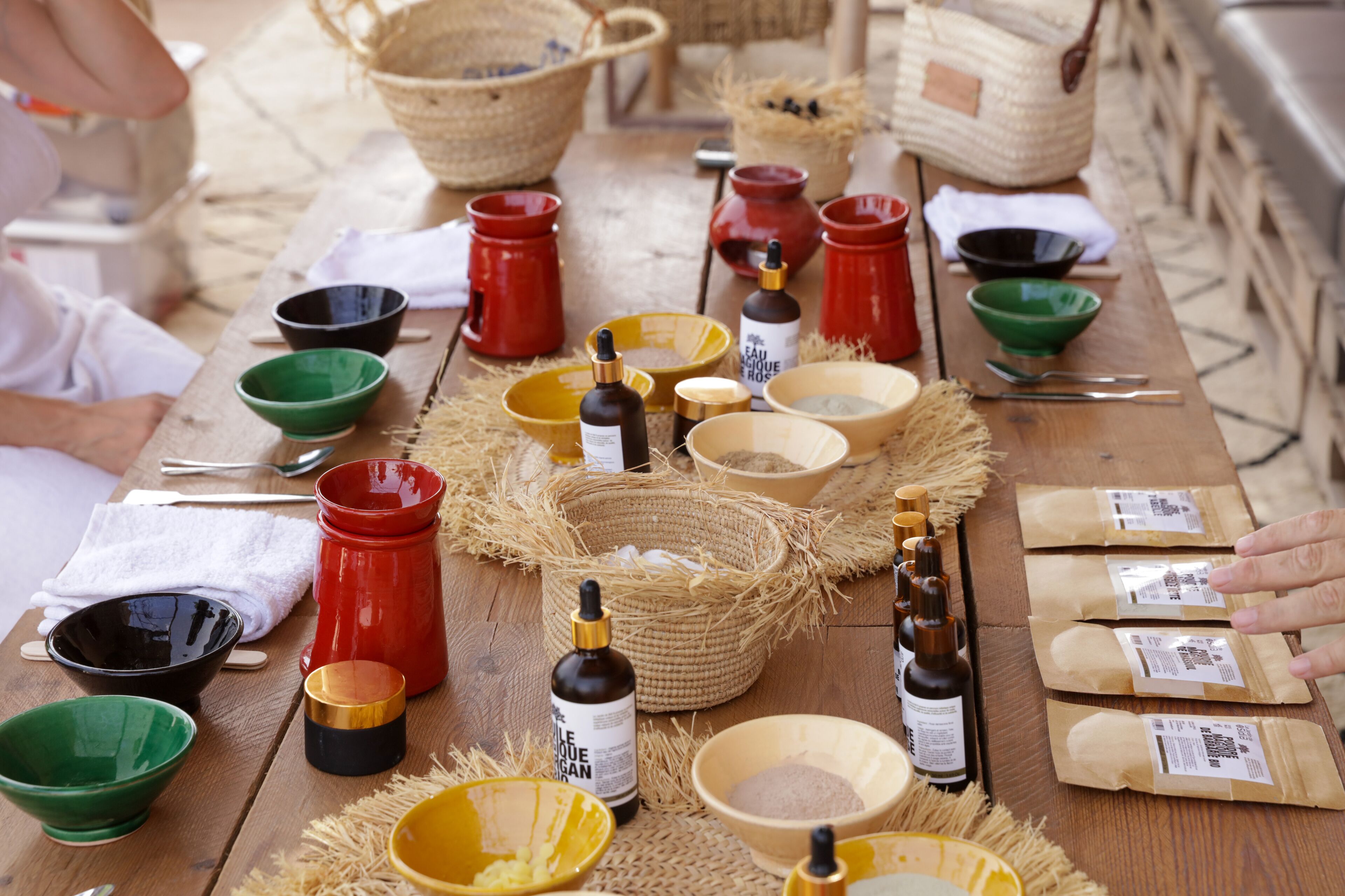 A wooden table with various containers, bottles, and woven baskets, likely used for food or drink preparation.
