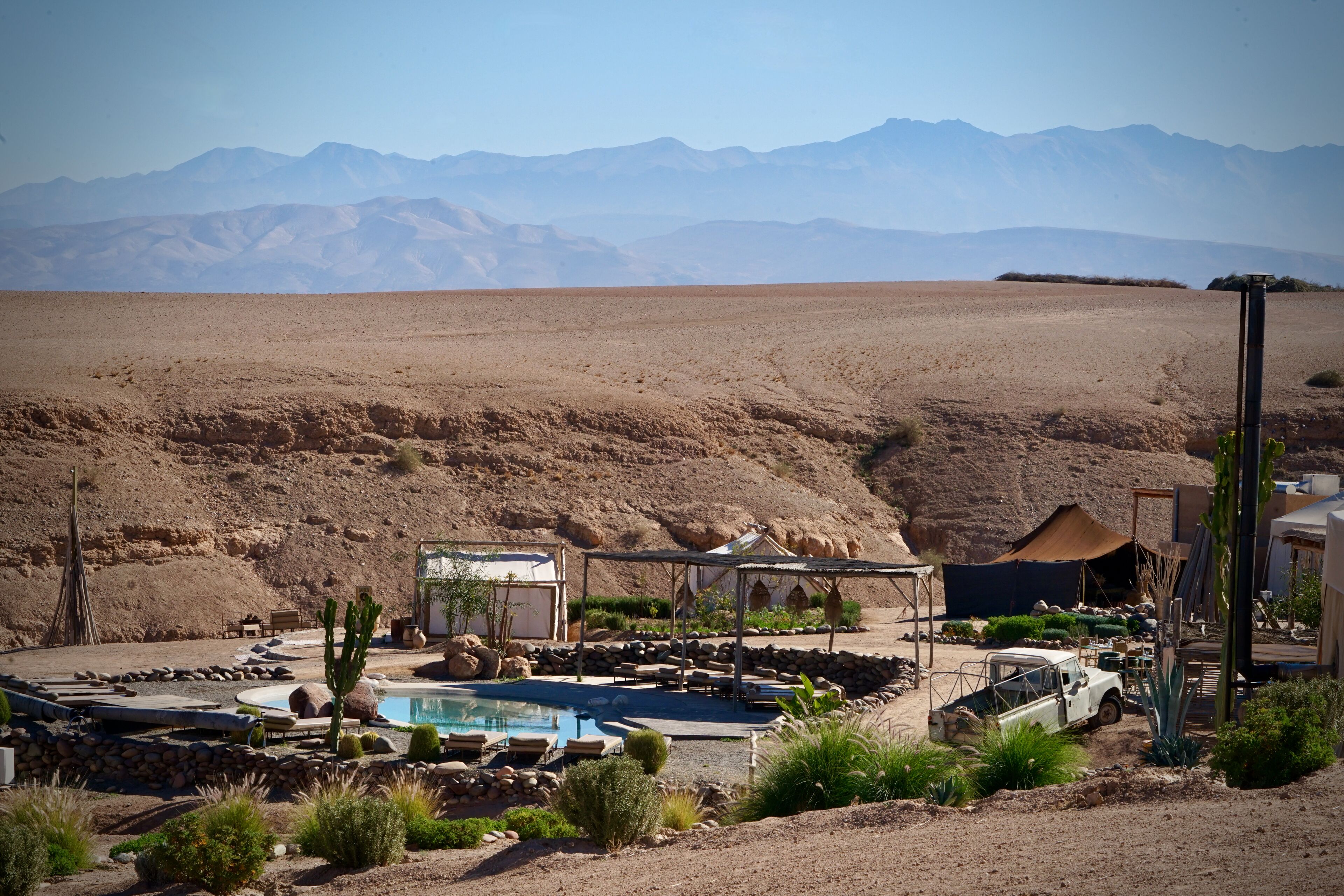 A desert resort with a swimming pool, outdoor seating, and a view of mountains.