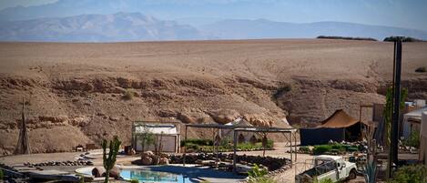 A desert resort with a swimming pool, outdoor seating, and a view of mountains.