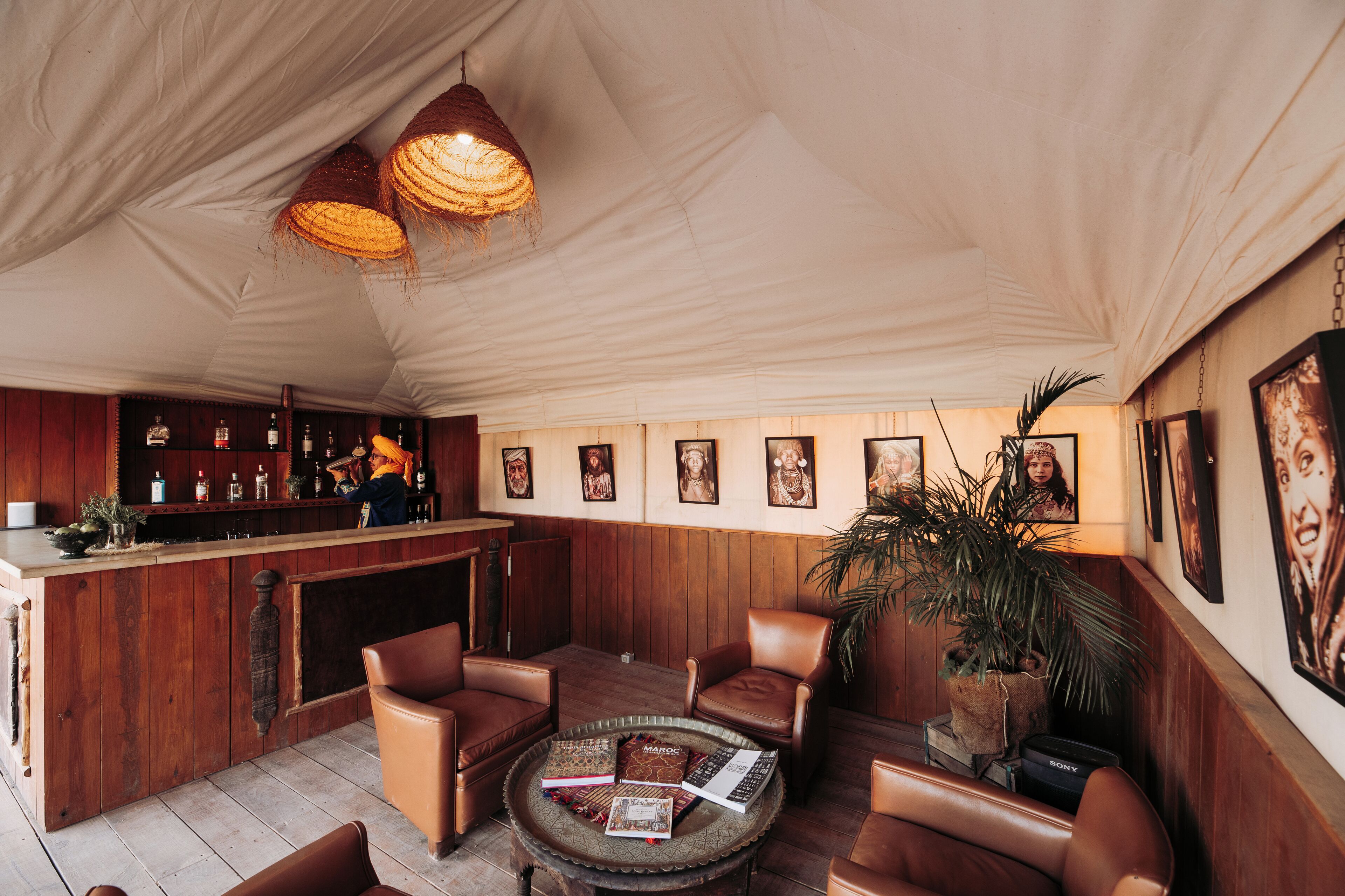 A bar area with wooden paneling, leather seating, and a bar counter with bottles.