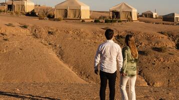 A desert landscape with tents and a couple walking.