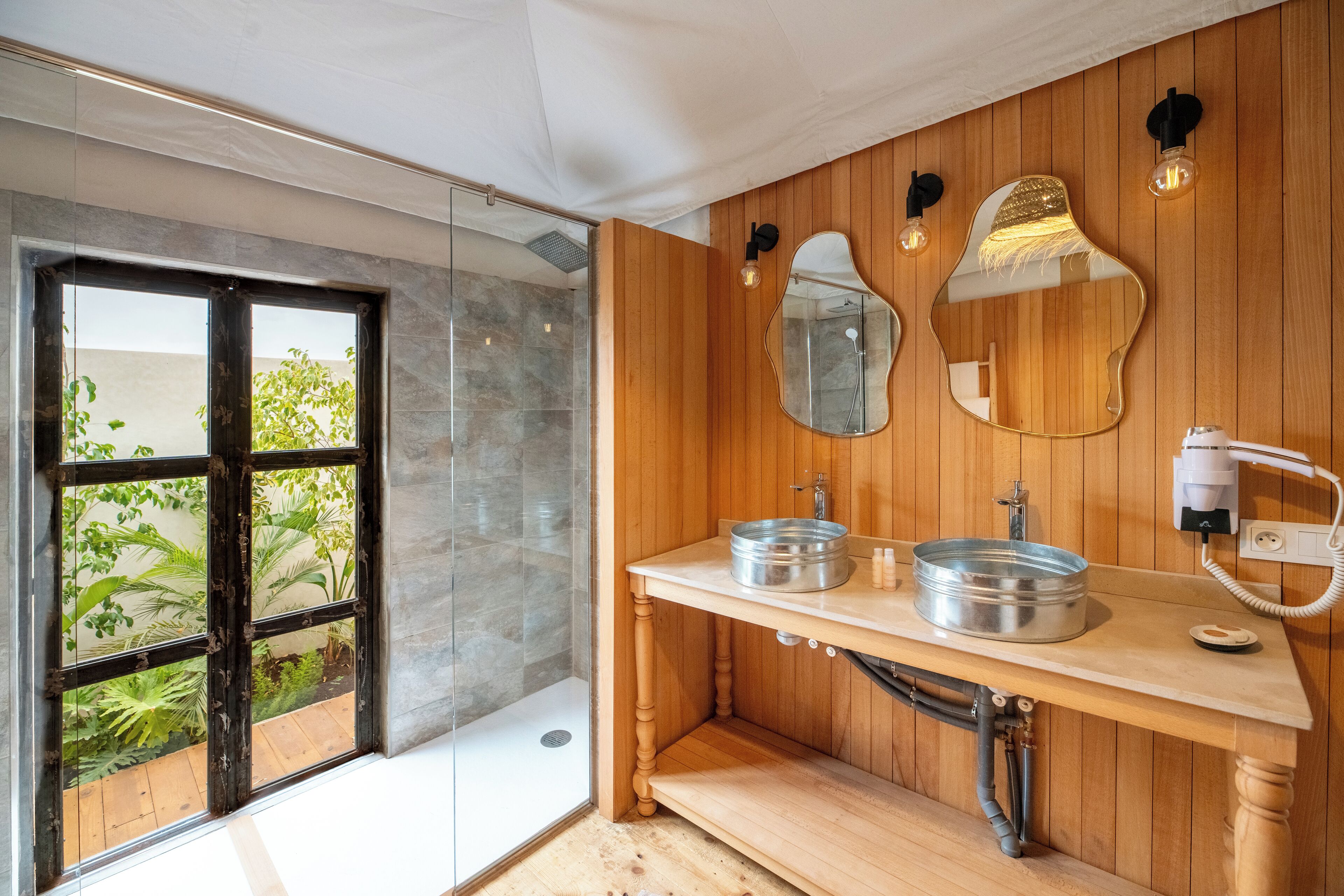 A modern bathroom with wooden paneling, a glass shower enclosure, and a sink with a round basin.