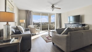 A modern hotel room with a living area featuring a sofa, armchairs, a TV, and a balcony with a view. - Yacht Club Villas #3-403 Spectacular Waterway View Condo! (North Myrtle Beach)