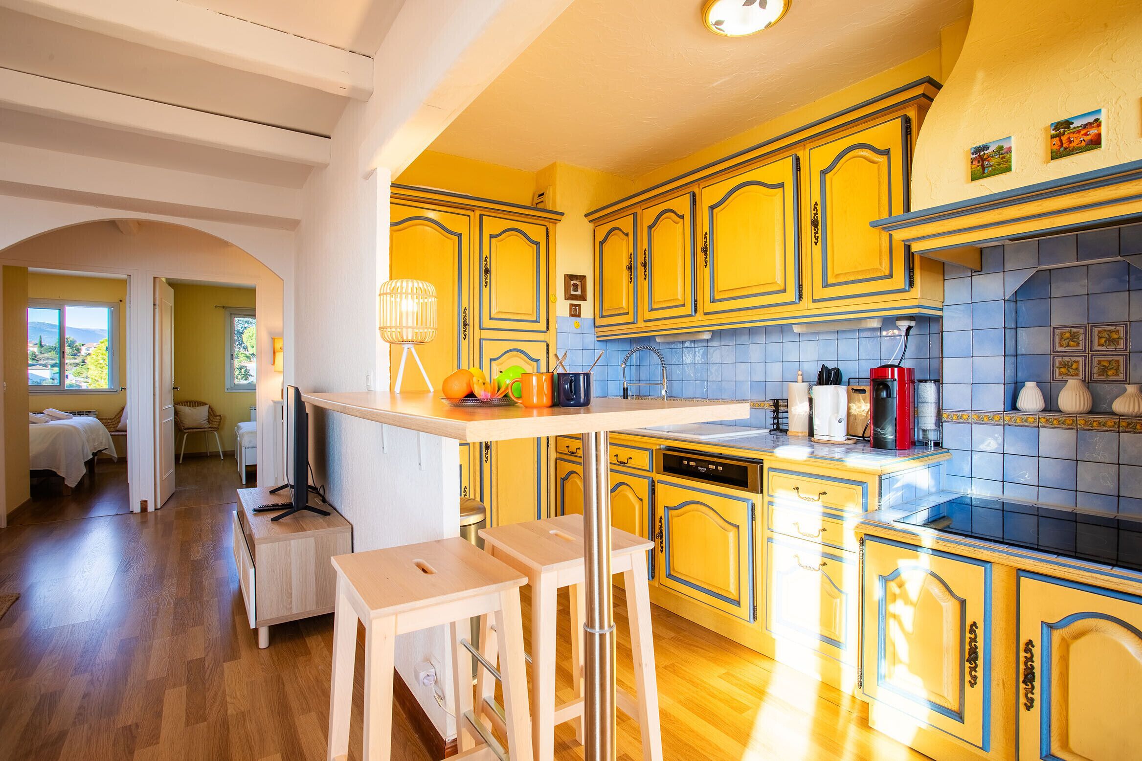 A kitchen with yellow cabinets, a wooden countertop, and a view of a bedroom.