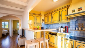 A kitchen with yellow cabinets, a wooden countertop, and a view of a bedroom. - LE JARDIN BLEU AP4388 By Riviera Holiday Homes (Niza)