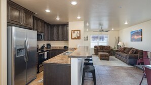 A modern kitchen with a stainless steel refrigerator, dark wooden cabinets, and a granite countertop.