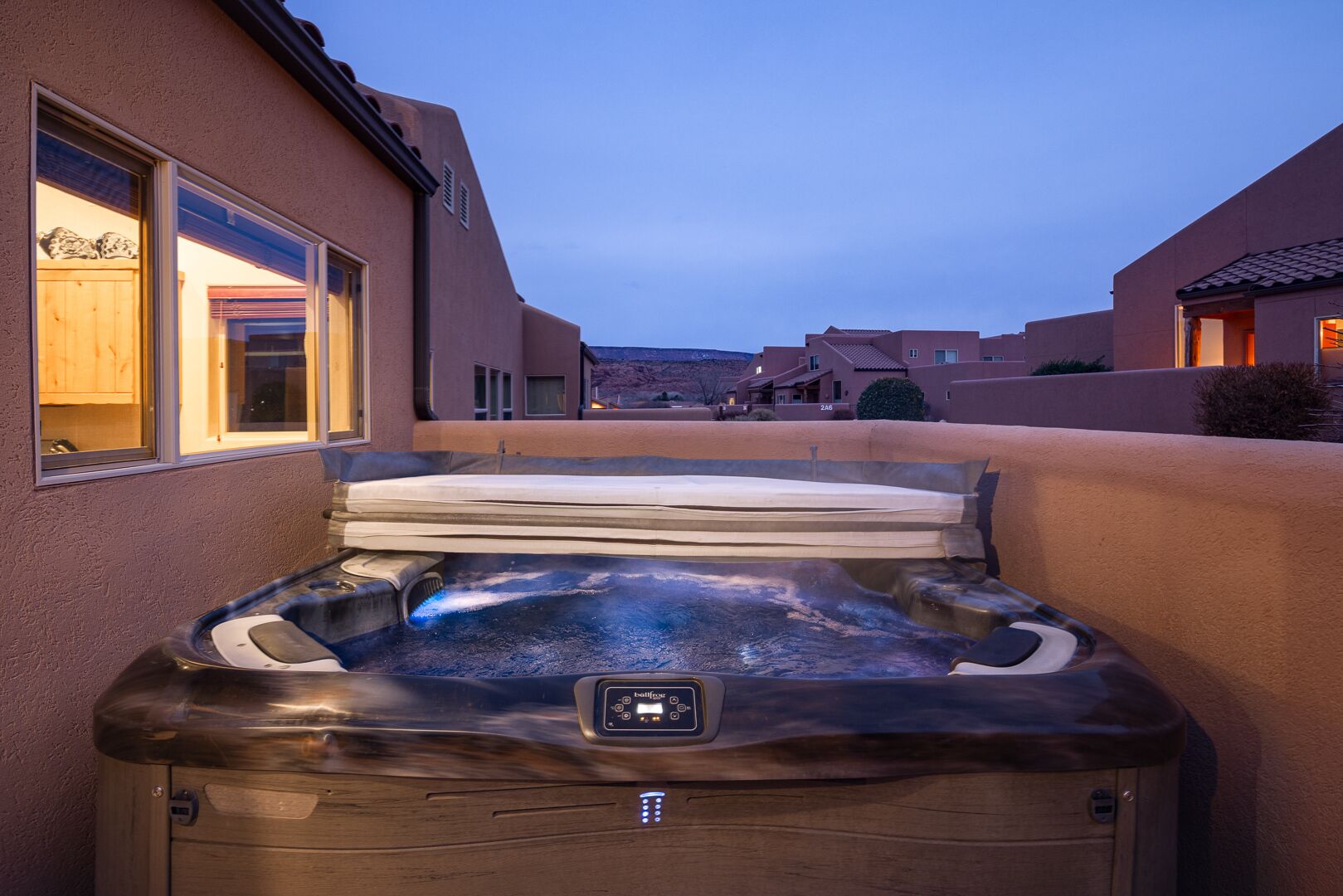 Un bain à remous situé dans un quartier résidentiel, offrant une vue dégagée sur les maisons environnantes et sur une chaîne de montagnes lointaine.