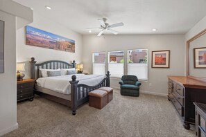 A bedroom with a bed, a chair, a dresser, and a ceiling fan.