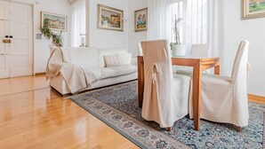 Ein modernes Wohnzimmer mit einem weißen Sofa, zwei Sessel, einem Holztisch und einem gemusterten Teppich.